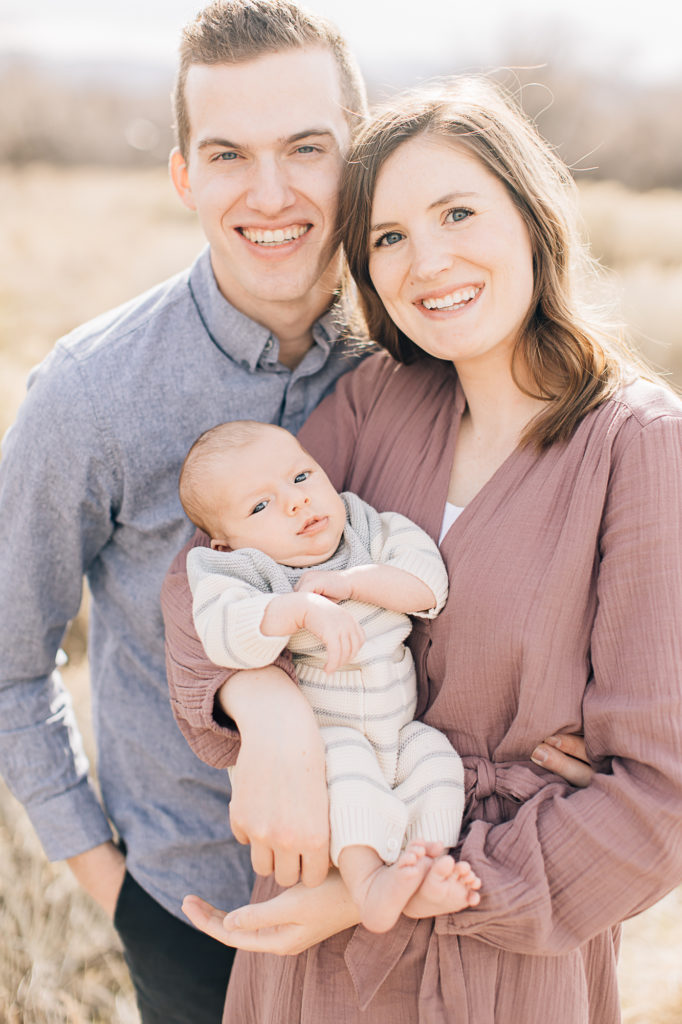 New family of three smile for a family portrait with a clean crisp edit by Kailee Matsumura Photography. clean bright crisp #KaileeMatsumuraPhotography #SLCphotographers #motherhood #newbornphotography #Utahfamilyphotography #babyportraits