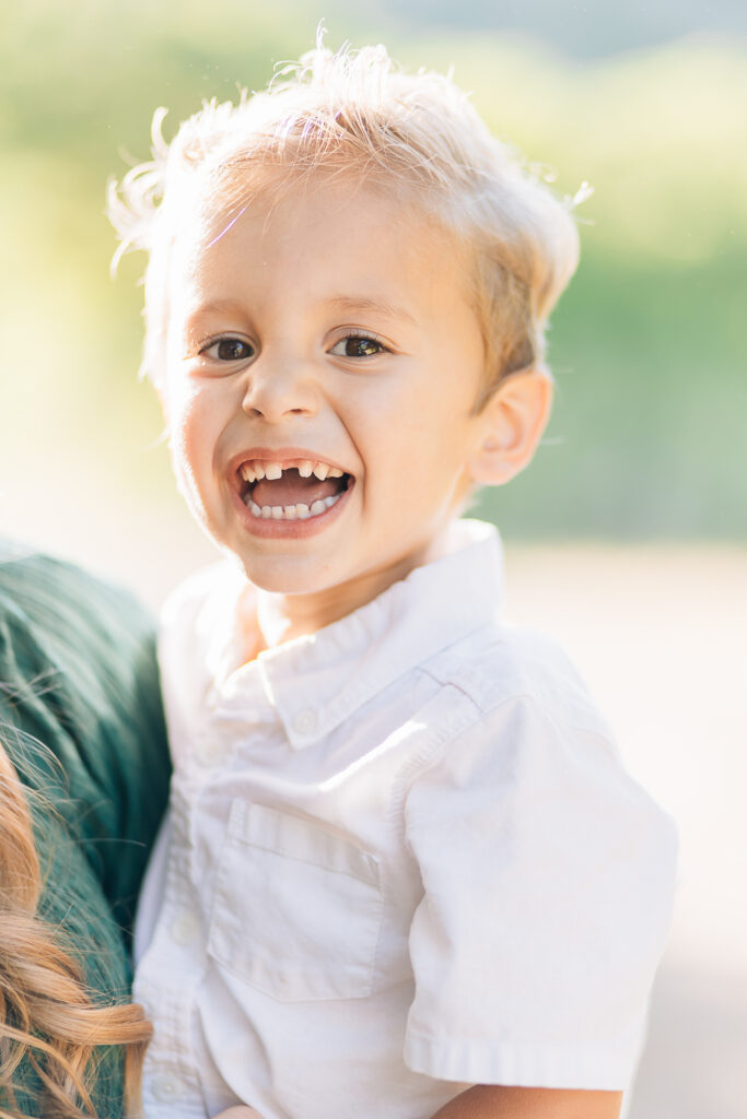 toddler boy smiling with missing tooth. Memphis Family Photographer. Blonde toddler in white collared shirt. What to wear for family photos. How to dress your toddler boy for family photos. Dressing toddler boy for family photos. Toddler boy family photo inspo. 