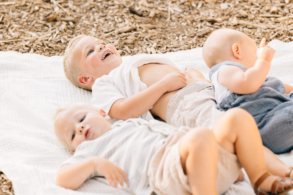 Boys with shirts up. Photos with chaotic boys. Three boys laying on a blanket. Memphis Family Photographer