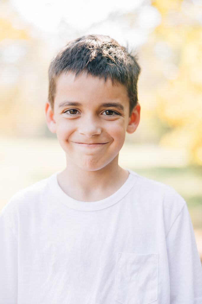 Shy boy smiles in a white t shirt. Photo taken in the fall in Memphis, TN by a Memphis Family Photographer