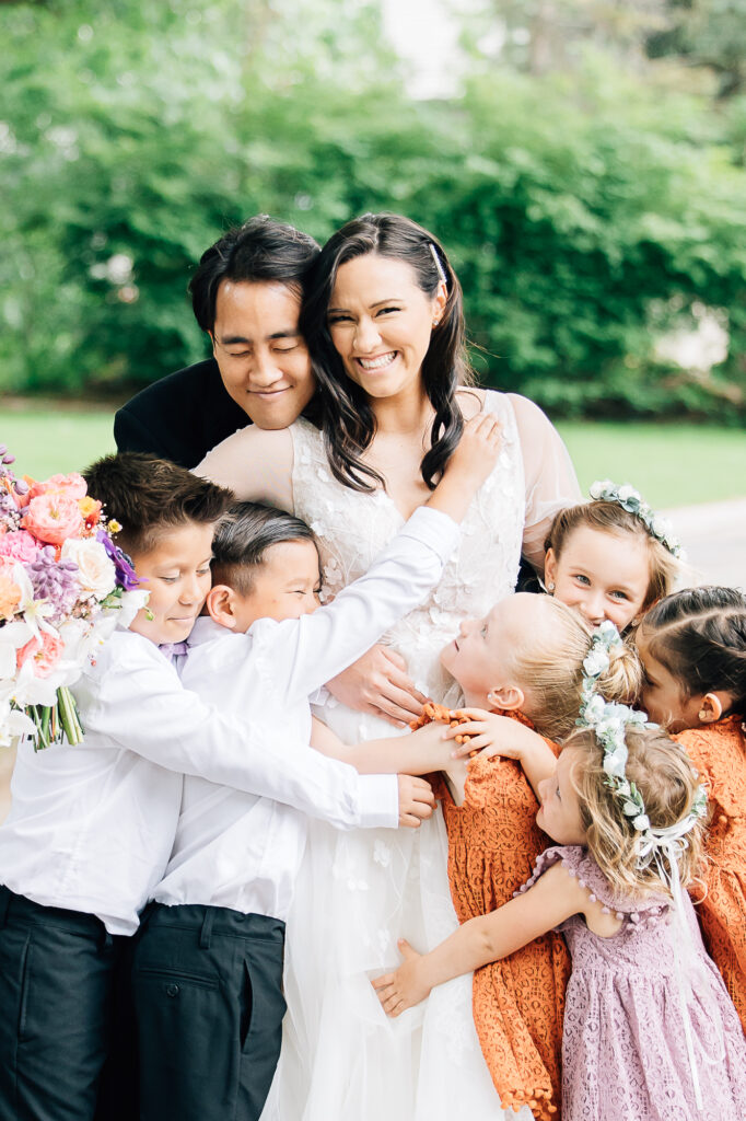 The flower girls and ring bearers hug the bride in groom during their wedding by Kailee Matsumura Photography. kid wedding outfit ideas kids in weddings #KaileeMatsumuraPhotography #Bartlett,TN #MemphisPhotography #KaileeMastumuraWeddings #TNweddingphotography #summerwedding #colorfulwedding