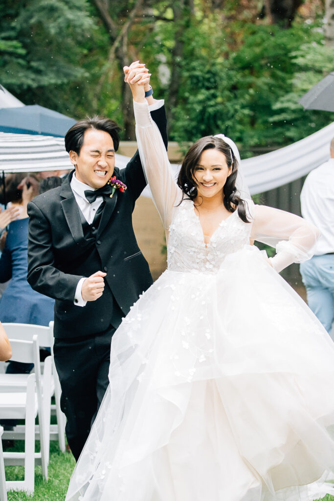A bride and groom hold hands and cheer as they walk down the aisle of their wedding by Kailee Matsumura Photography. wedding photographers walking down the aisle she said yes #KaileeMatsumuraPhotography #Bartlett,TN #MemphisPhotography #KaileeMastumuraWeddings #TNweddingphotography #summerwedding #colorfulwedding