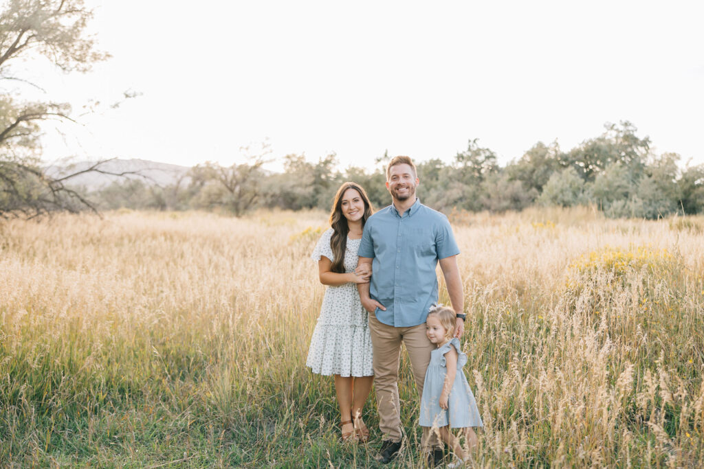 Family smiles in a field of wild grass in Bartlett, Tennessee by professional photographer Kailee Matsumura offering family photography in the Memphis, TN area. #familyphotos #familyoutfitinspo #tennesseephotographer