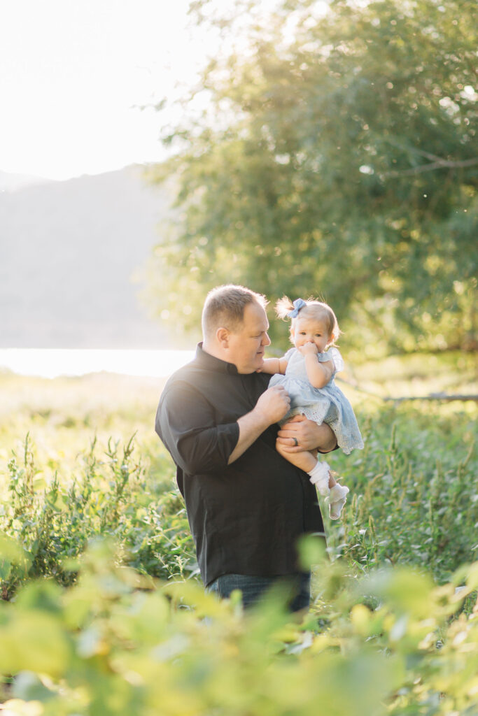 Sweet dad holds his baby daughter in a field with golden light behind them during a Kailee Matsumura Photography outdoor photo session. Photos taken during golden hour.
#KaileeMatsumuraPhotography #FamilyPictures #TipsForFamilyPhotos #TennesseeFamilyPhotographer

