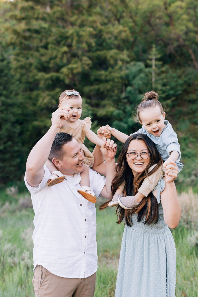 Kailee Matsumura Photography captures the most darling family during outdoor family photo session. Mom and dad each hold a child on their shoulders while everyone is laughing.
#KaileeMatsumuraPhotography #MemphisFamilyPhotographer #TennesseFamilyPhotos #​​BartlettFamilyPhotographer #OutfitTips
