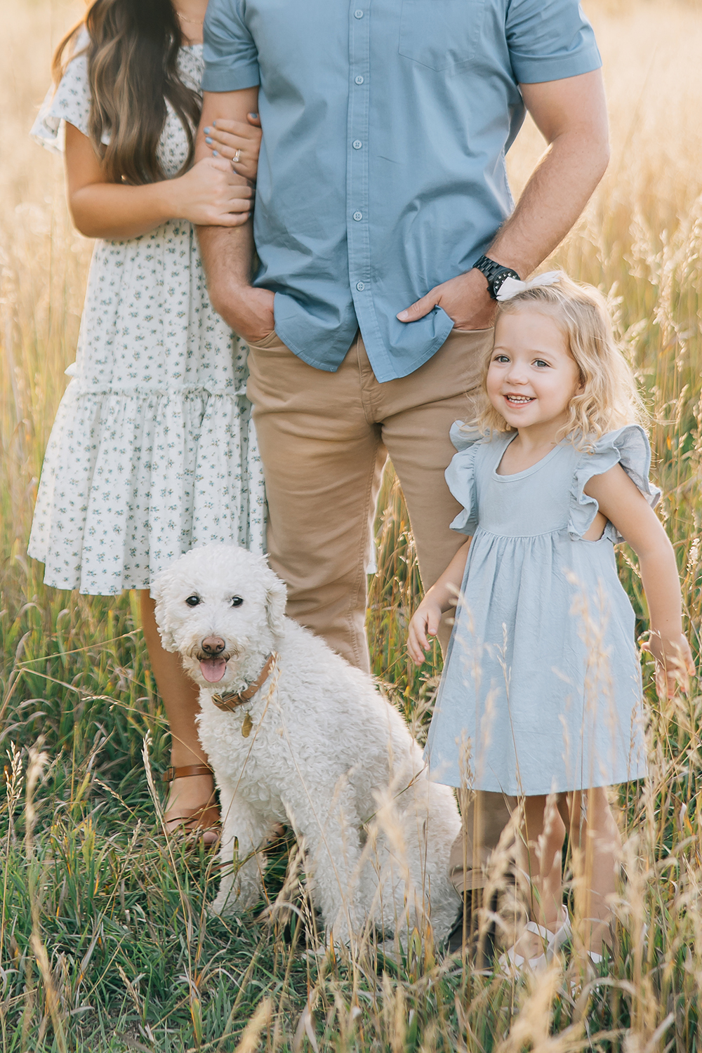 A toddler girl in a spring dress is excited about family pictures in a grass field of Tennessee with natural lighting to complement the outfit color scheme. Family outfit inspo family pet kids outdoor location comfortable clothing personal style #outdoorfamilyphotography #Tennessefamilyphotographer #mississippifamilyphotographer #tipsforsummerfamilyphotos

