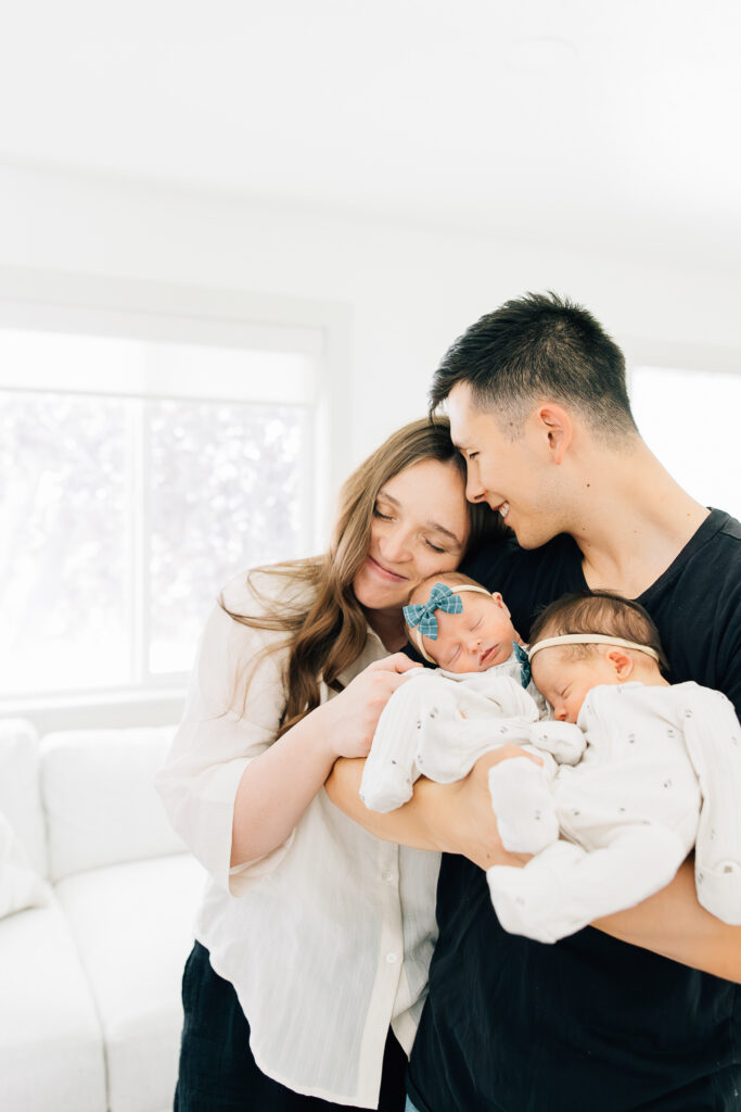 a new family of four with twin girls poses and snuggles together for a portrait in their home during their newborn photoshoot with Kailee Matsumura, a Memphis Newborn Photographer. 