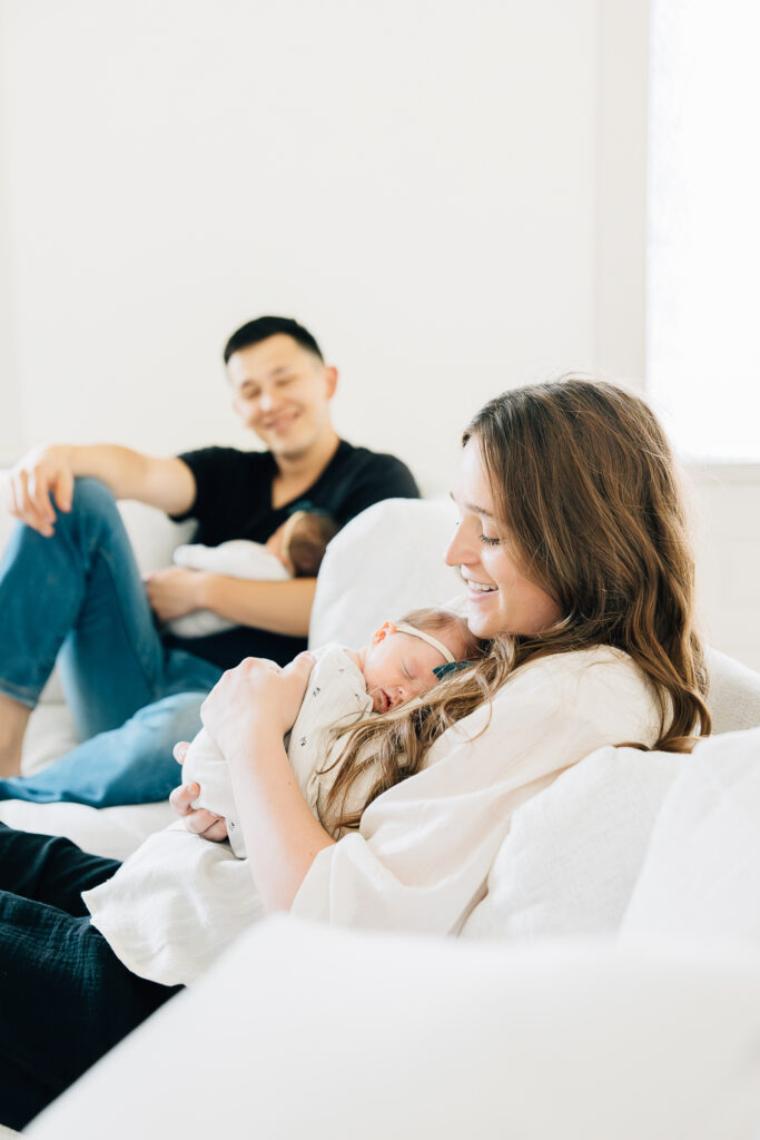 A dad looks lovingly at his wife, a mother now, as they hold their twin girls. 