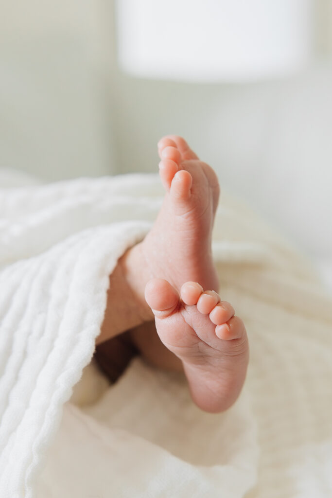 Small baby feet with a cream gauze blanket. Memphis Newborn Photographer. 
