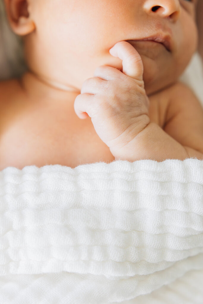 newborn with their hand by their mouth during their newborn photos with a Germantown Newborn Photographer. 