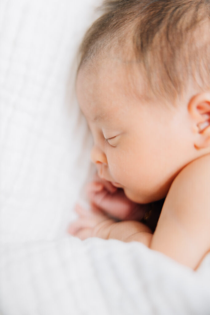 Close up shot of a newborn baby with a cotton gauze, cream colored blanket focusing on her closed eyes, little nose. Memphis Newborn Photographer. 