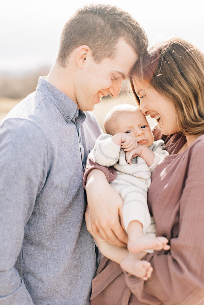 Outdoor Newborn Photography shoot. Mom and Dad smile with their newborn baby boy. Newborn colors of blue, pink, white and gray. Photos taken during the fall, so fall newborn photoshoot with Kailee Matsumura Photography, an award winning Memphis Newborn Photographer. 
