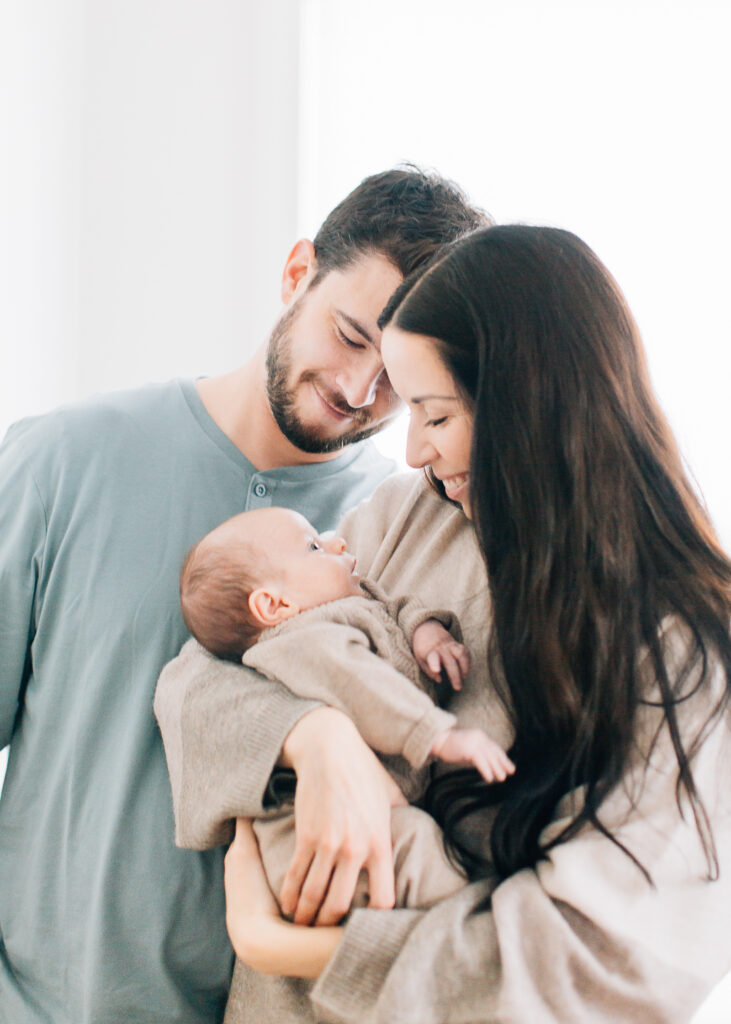 Fall Newborn Photos, Neutral cozy newborn photos, Newborn boy photos. Mom and dad look down at baby boy during their in home session with Kailee Matsumura, a Memphis Newborn Photographer.