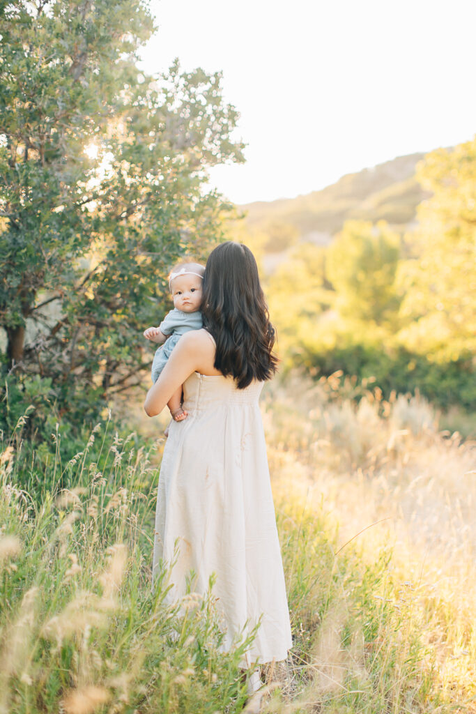 Mom walks with newborn daughter peering over her shoulder at Shelby farms in Germantown, TN during her newborn session. 