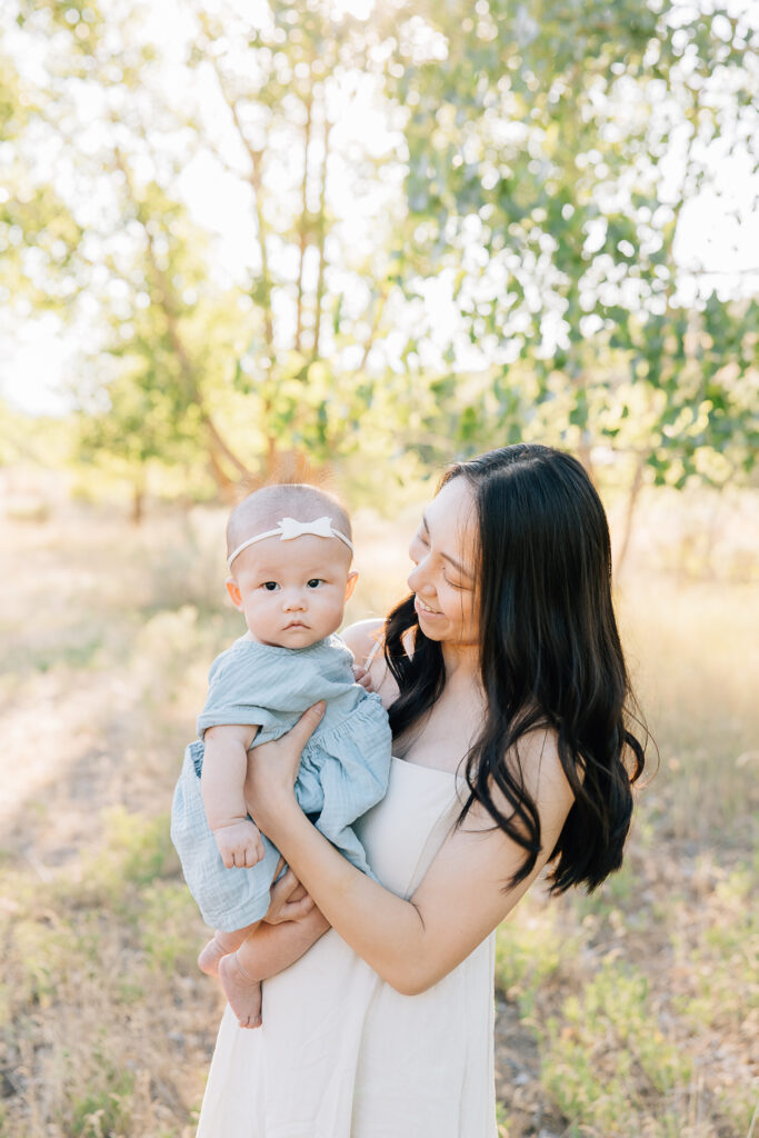 Mom smiles at newborn baby during outdoor newborn session. 