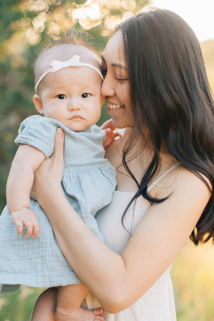 Mom smiles with newborn baby in her arms. Linen dresses. Blue and cream color pallet. Summer outfit inspo for newborn photos. 