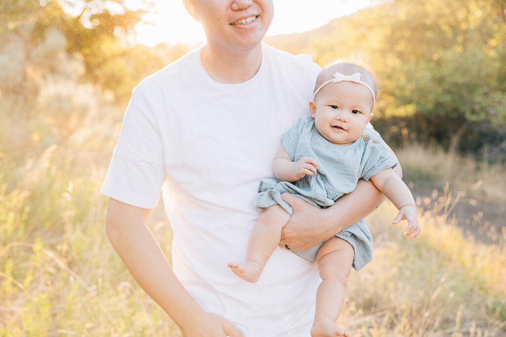 Newborn girl smiling with dad during her outdoor newborn session in Germantown with Germantown Newborn Photographer, Kailee Matsumura. 