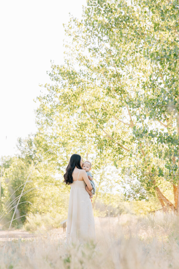 Mom snuggles newborn girl. Wearing summer colors- summer family photo inspo. 